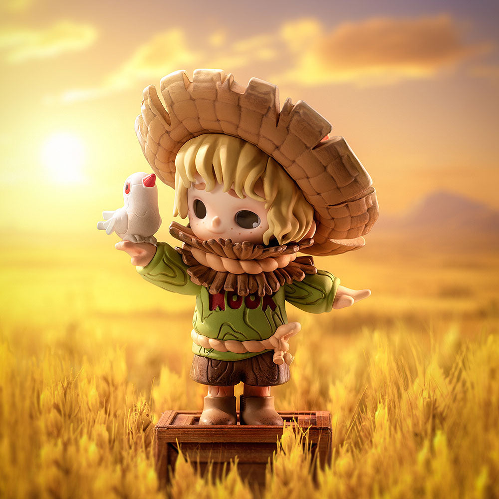 Figurine of a character with a large hat holding a small creature in a field with a sunset background
