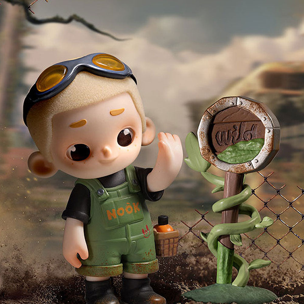 Toy figure of a child in overalls with goggles, standing next to a 'wild' sign in a natural setting.
