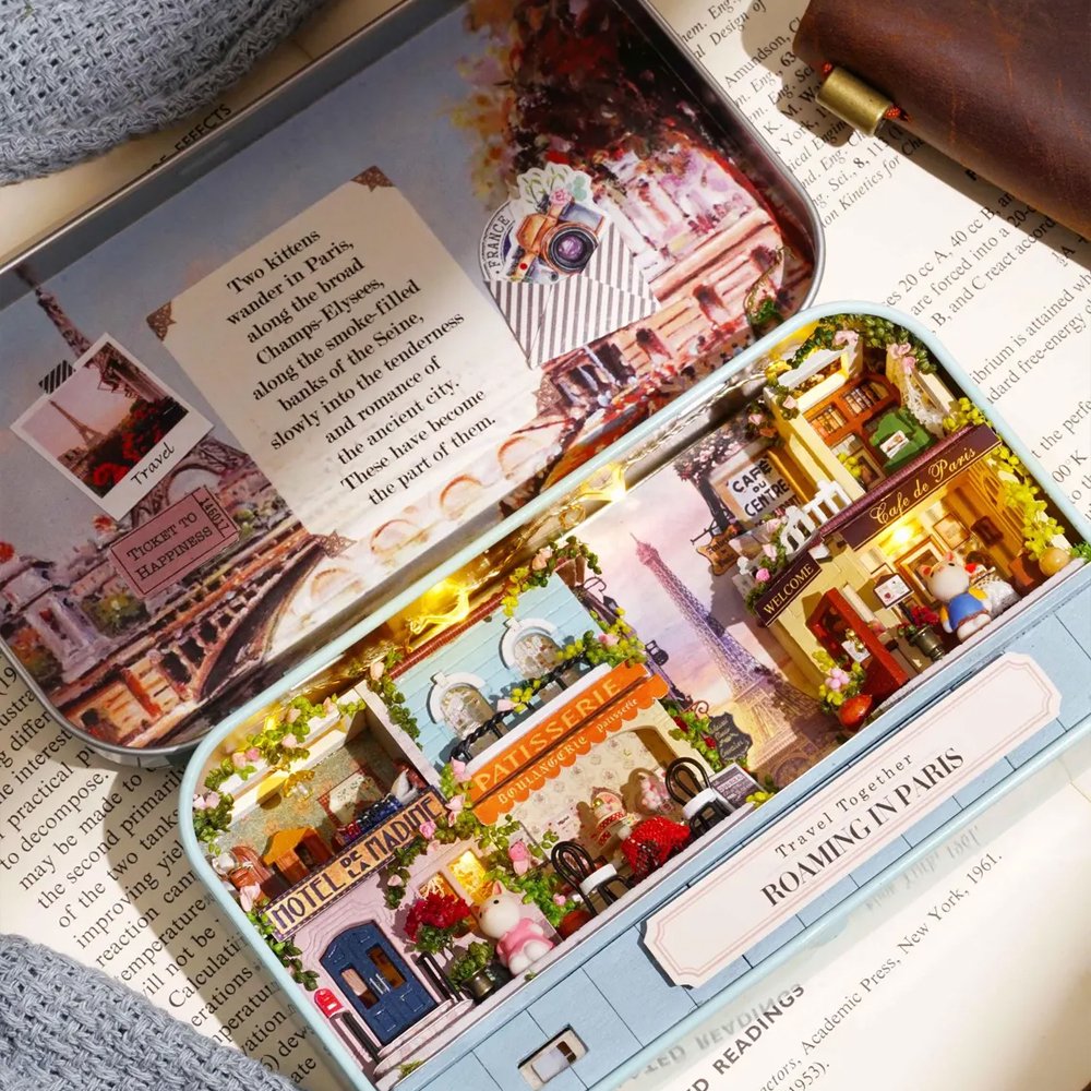 A intricate DIY miniature kit replicating a traditional Parisian cafe with a European designed facade, outdoor seating, and warm LED light