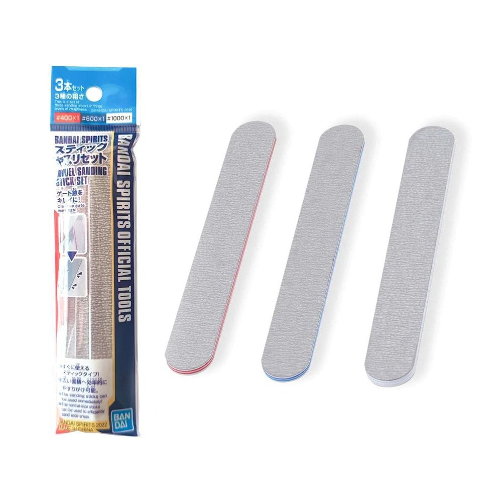 A set of three Bandai Spirits model sanding sticks in their retail packaging, featuring red, blue, and white color-coded edges. Each gray abrasive stick is displayed next to the package to show the different grit levels for plastic model finishing.