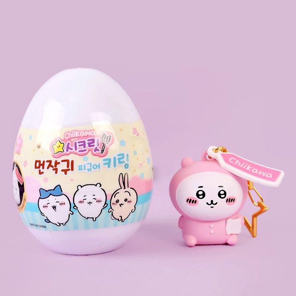 Pink chiikawa keychain with a colorful egg-shaped container on a light purple background