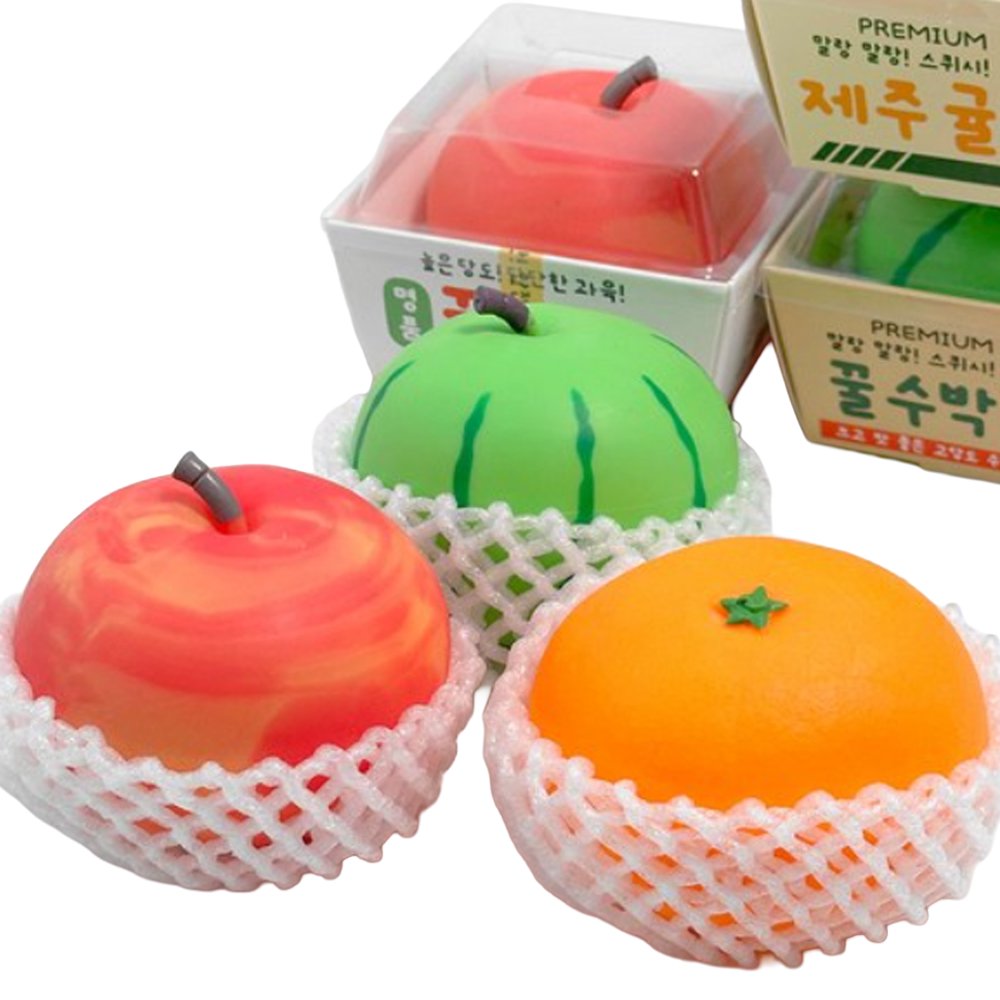 Vibrant fruit-shaped squishy stress toys styled like fresh apples, tangerines, and watermelons sitting in white foam protective netting and mini cardboard crates