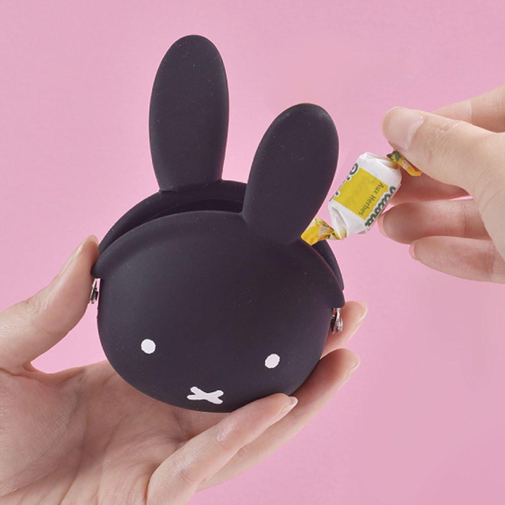 A close-up photograph of a woman's hand holding a small, jet black Miffy character pouch made of soft, flexible premium silicone. Part of the Official Miffy Mini Pochibi series, aesthetic alternative; a durable, tactile, and minimalist Zen bunny purse designed for adult mental wellness and nostalgic daily organization.