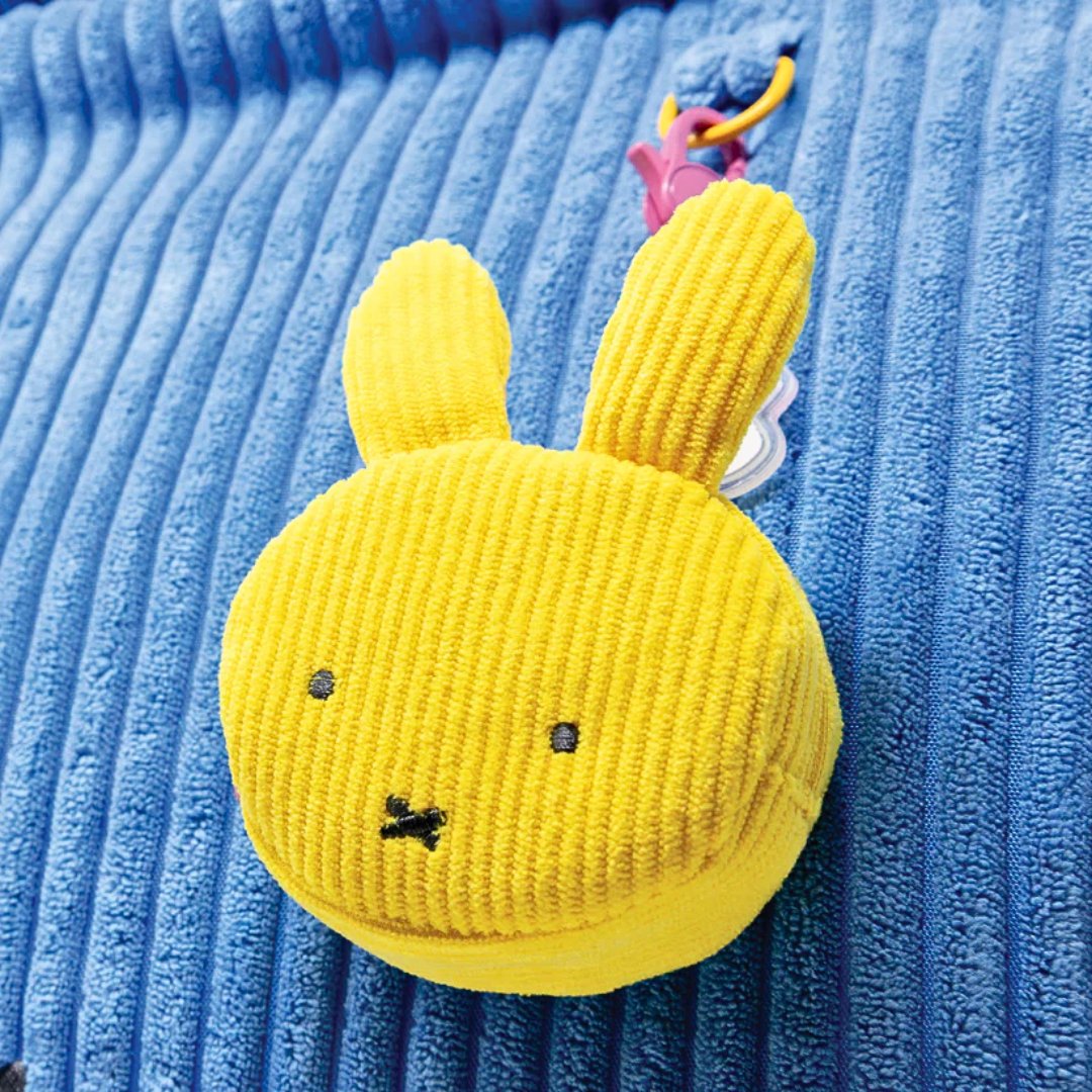Officially licensed Miffy face shape Yellow corduroy pouch toy with n a blue textured background