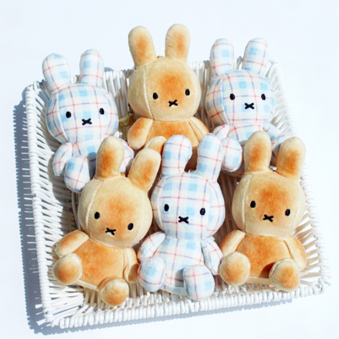 Officially licensed Miffy plush keychains seated in a white basket. The set includes two styles: bread or toast with its orange-brown color, and one in a light blue, white, and red plaid/checkered fabric. Both Miffy dolls feature embroidered eyes and the signature 'X' mouth.