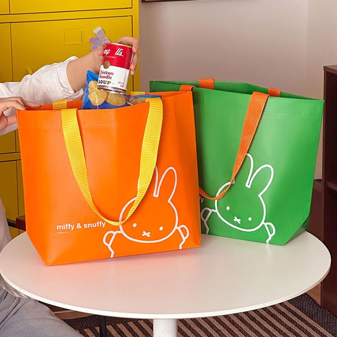 Officially licensed Miffy & Snuffy Reusable Tote Bags . The bags are Made from durable, wipeable tarpaulin material, featuring one in bright orange with yellow handles and Miffy, and one in green with orange handles and Miffy. Ideal for shopping, groceries, or carrying goods.