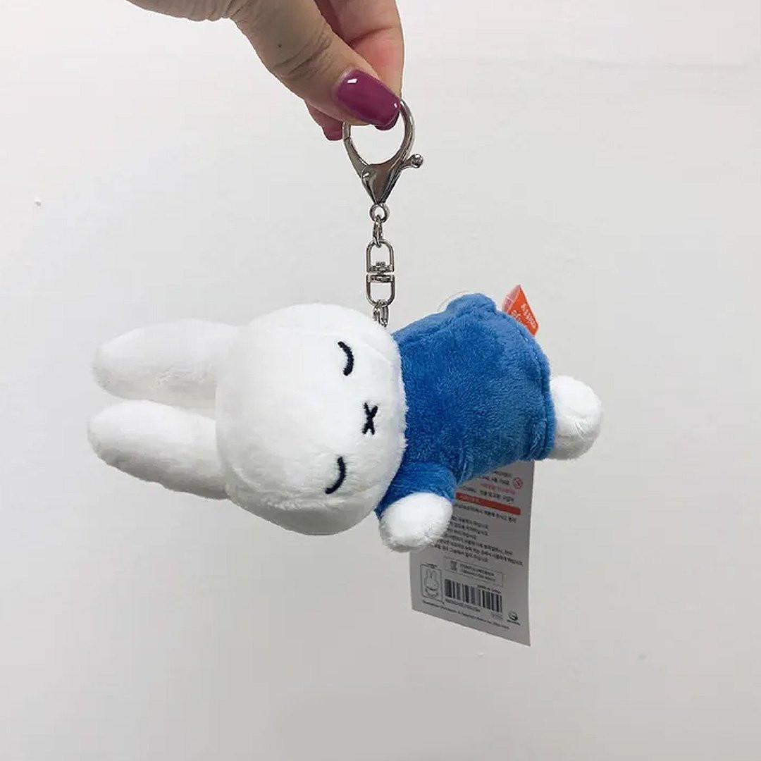 Officially licensed Miffy sleeping plush keychain featuring embroidered closed eyes and an 'X' mouth. Miffy plush wearing blue top. Ideal collectible bag charms, backpack zipper pulls or gift.