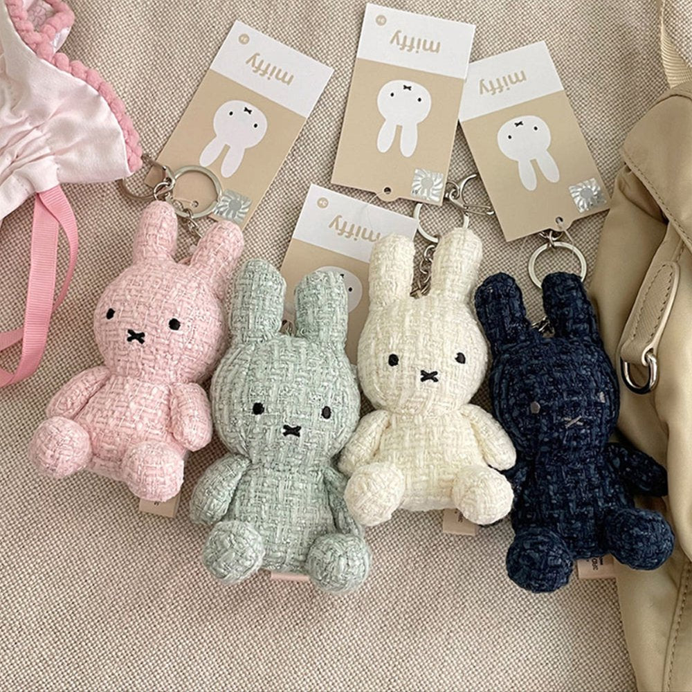 Four officially licensed Miffy textured tweed plush keychains lined up in pink, sage green, cream, and navy blue with attached silver keyrings