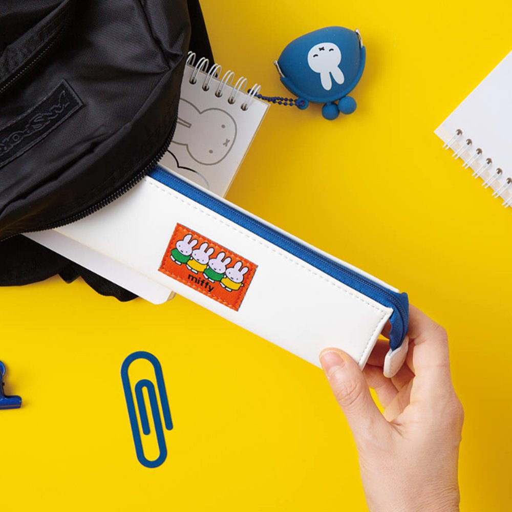 Two officially licensed slim, triangular Miffy pencil cases, featuring one in bright yellow with a white zipper and a "miffy & dan" patch, and the other in cream-colored with a bold blue zipper and a red "miffy" patch.