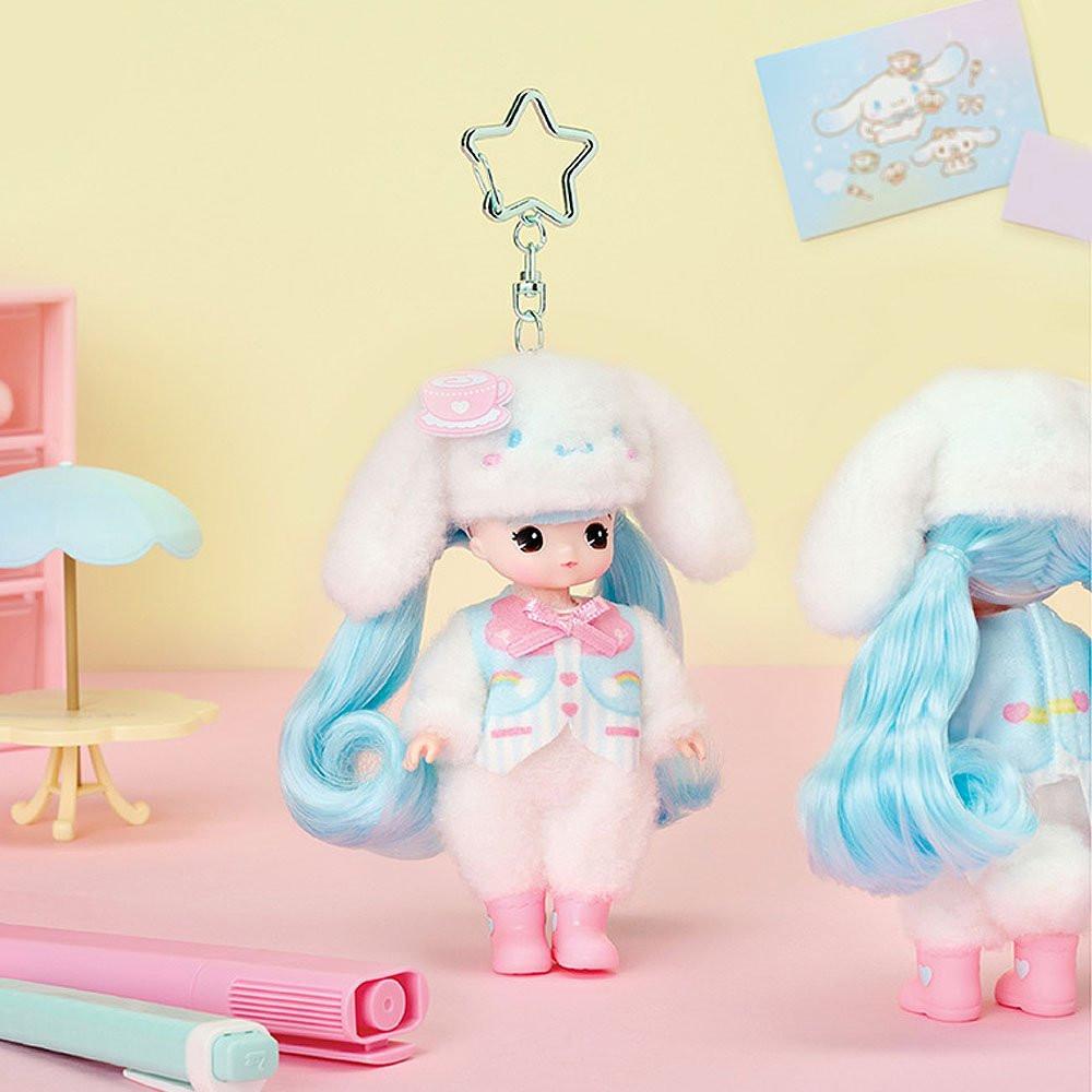 Officially licensed Sanrio and Little Mimi Collaboration Doll Keychain Collection featuring a blonde mini doll wearing a fuzzy white Cinnamoroll plush hat decorated with a pink teacup icon, a pastel blue and white striped vest with pink hearts and rainbow graphics, and pink boots, attached to a silver star shaped metal clasp over a pale yellow background, ideal for adult kidult collectors as a cute aesthetic backpack charm or nostalgic collectible accessory.