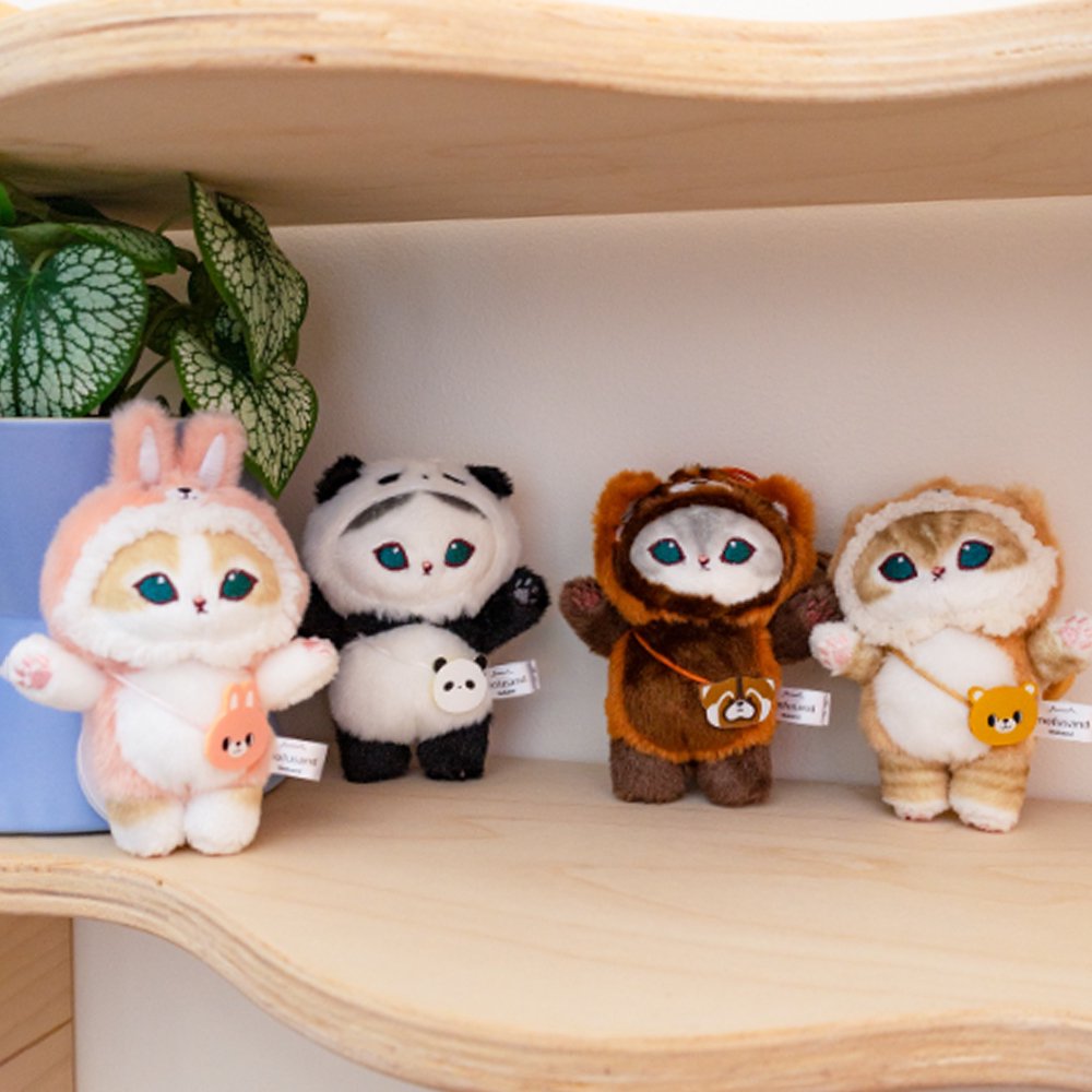 An officially licensed collection of four Mofusand plush cat charms in animal costumes: Pink Bunny, Giant Panda, Red Panda, and Brown Bear displayed on a shelf. Easy to attach to keys, totes, pants or backpacks with a clip-on chain.