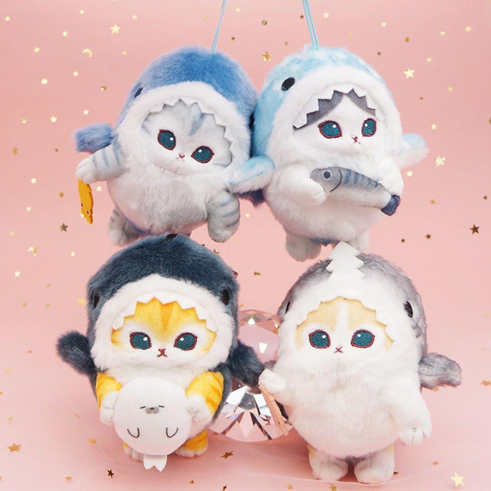 An officially licensed Mofusand shark cat plush keychain featuring a fluffy blue tabby kitten wearing a blue shark onesie with embroidered details
