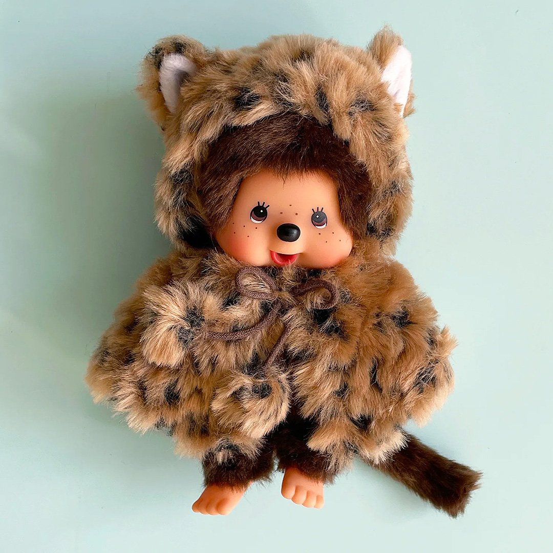 Officially licensed by Sekiguchi Japan, Monchhichi girl dressed in a leopard-print hood complete with cat ears, tail with her signature thumb-sucking pose. she’s perfect for cuddling, displaying, or gifting to Monchhichi fans of all ages.