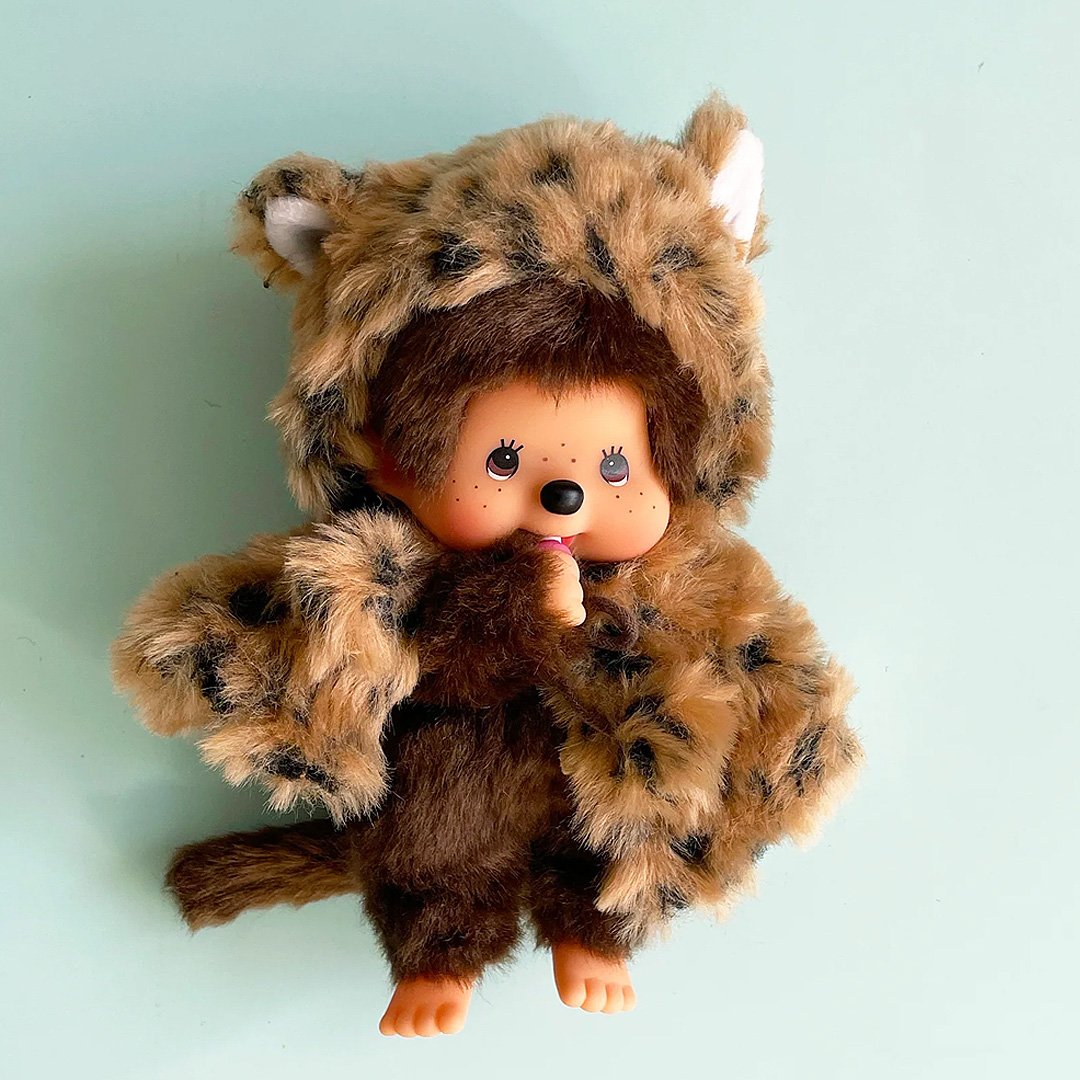 Officially licensed by Sekiguchi Japan, Monchhichi girl dressed in a leopard-print hood complete with cat ears, tail with her signature thumb-sucking pose. she’s perfect for cuddling, displaying, or gifting to Monchhichi fans of all ages.