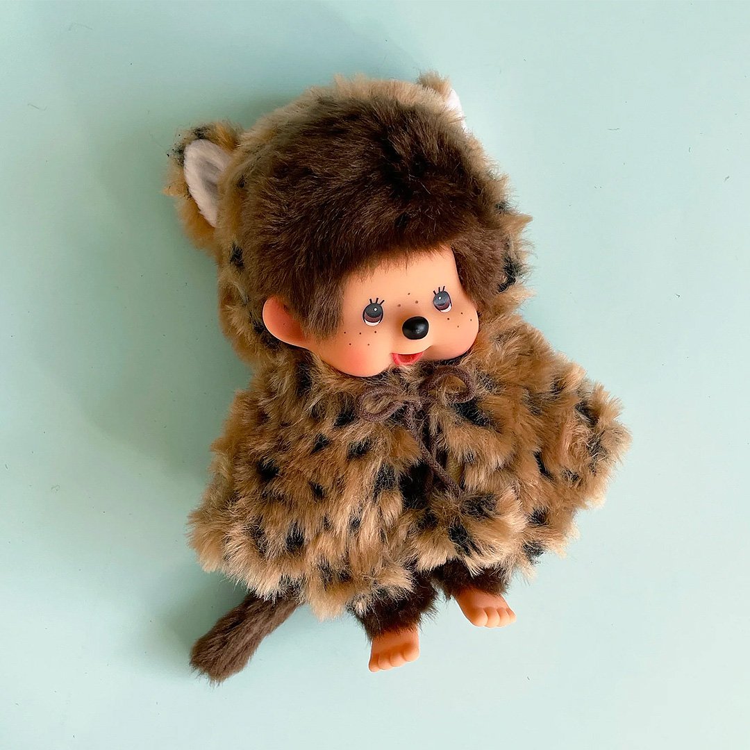 Officially licensed by Sekiguchi Japan, Monchhichi girl dressed in a leopard-print hood complete with cat ears, tail with her signature thumb-sucking pose. she’s perfect for cuddling, displaying, or gifting to Monchhichi fans of all ages.