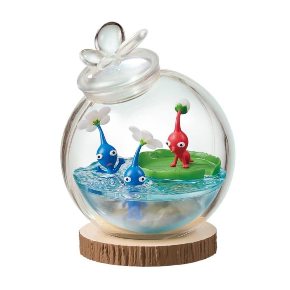 Officially licensed Re-Ment Pikmin Terrarium Collection Figure featuring one Red Pikmin on a giant green water lily pad and two Blue Pikmin in the clear 'water' base. All are enclosed in a round clear glass globe with a water drop design stopper, placed on a wood slice base.