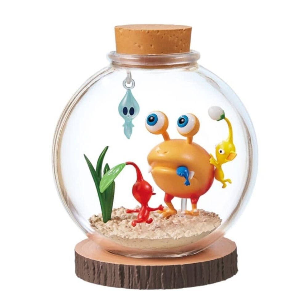 A collectible figurine of the characters from the video game series Pikmin inside a clear glass jar with a cork stopper and a wood-grain base, set against a plain white background.