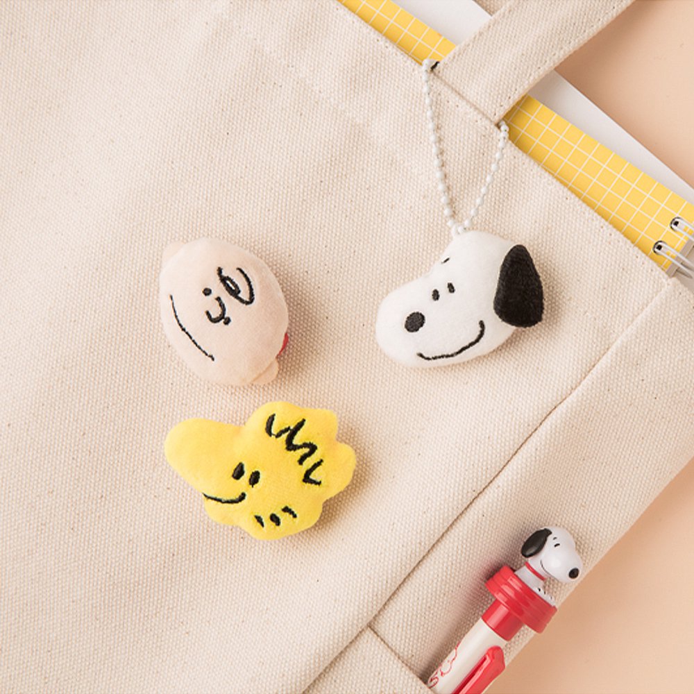 Officially licensed Peanuts plush keychains featuring the faces of Snoopy, Charlie Brown, and Woodstock attached to a white ball chain.