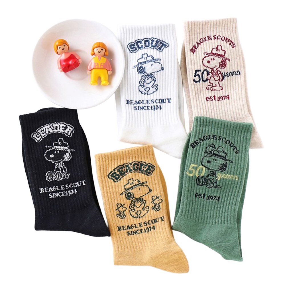 A set of five crew-length socks in black, beige, white, green, and mustard yellow. Each sock features an embroidered graphic of Snoopy as a Beagle Scout leader.
