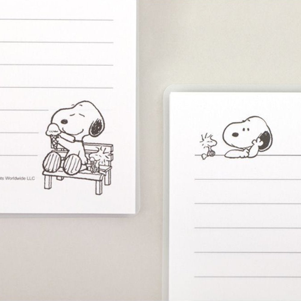 Three officially licensed Peanuts line notebooks with translucent covers in soft hues of pink, yellow, and green, each featuring a large illustration of Snoopy. The interior view shows 8mm ruled pages with small Snoopy graphics at the top and bottom corners.