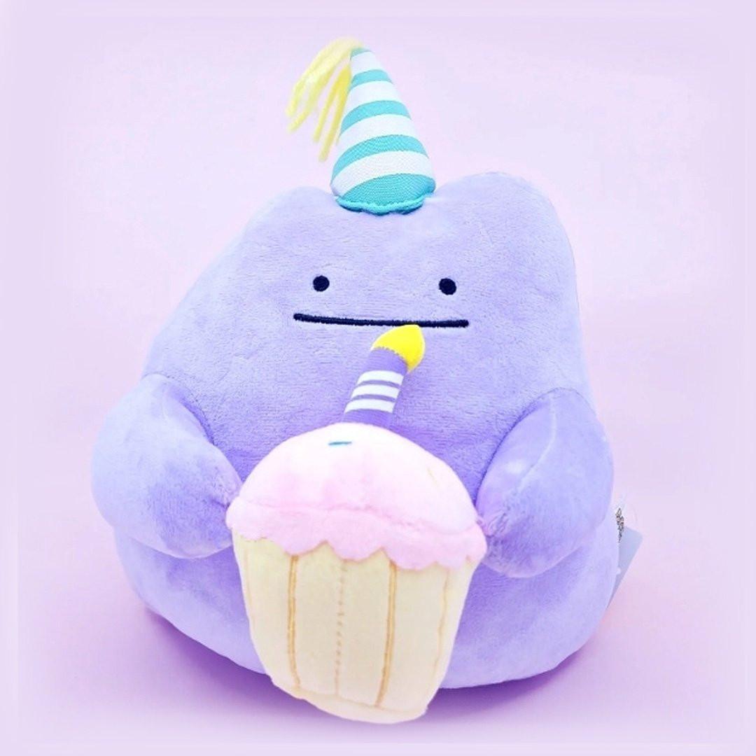 Officially licensed Pokemon plush Ditto wears a charming party hat topped with a bright yellow tassel, and holing a cake for celebrating a special day.