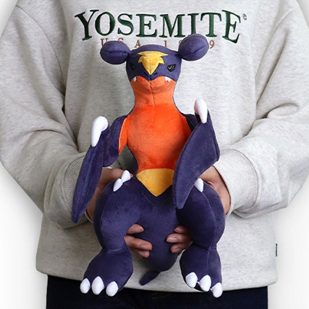 Pokemon Garchomp Plush toy of a character with orange, purple, and yellow colors on a white background