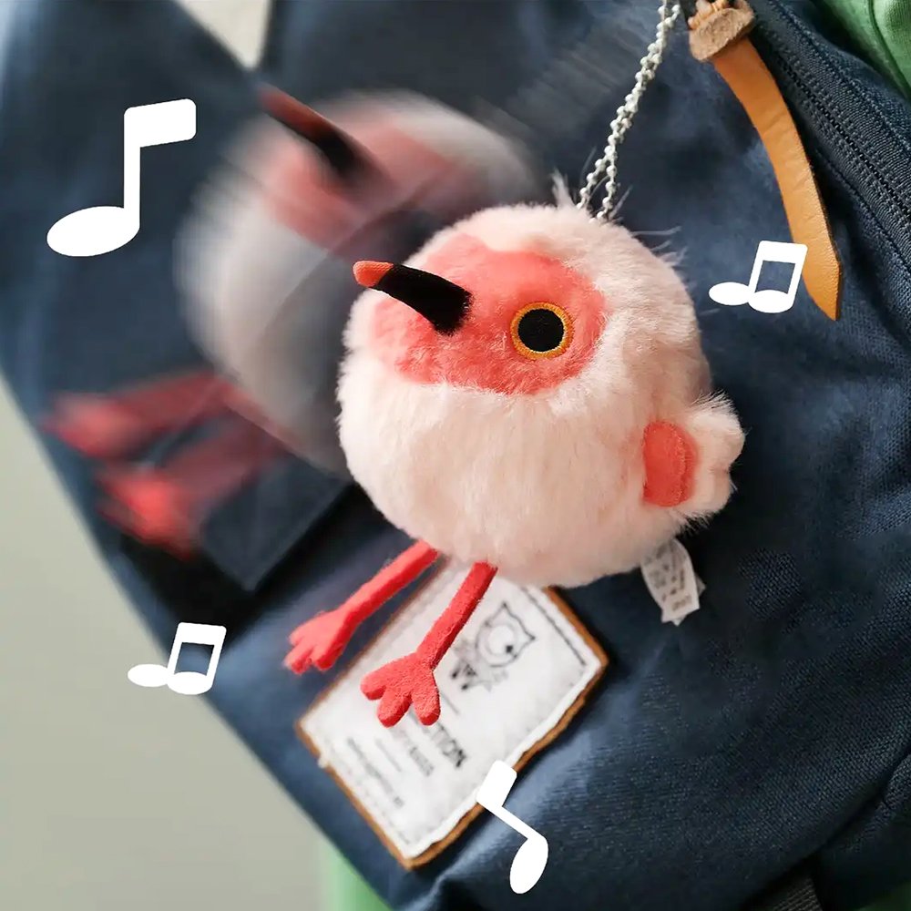 A round, light pink Crested Ibis bird plush keychain with a bright red face, red feet, and a wispy white crest