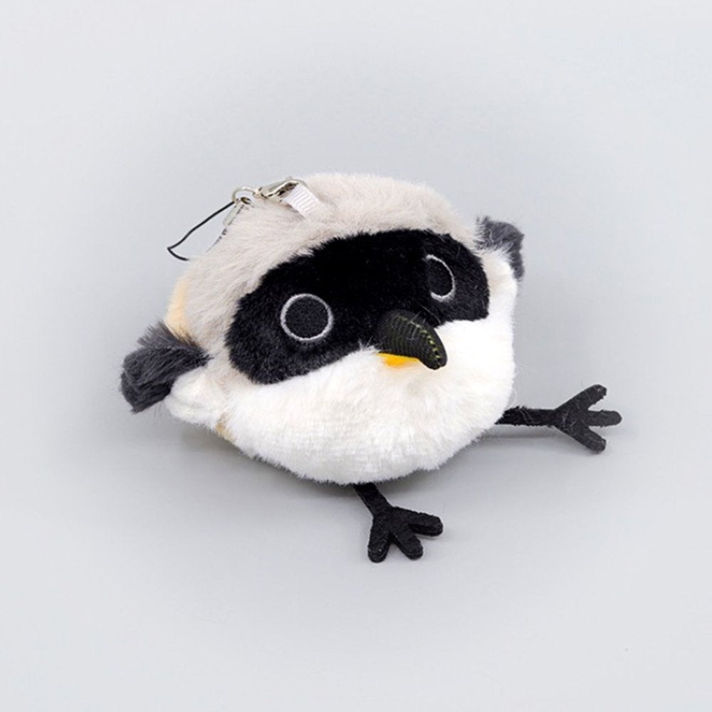 A round, fluffy Long-tailed Shrike bird plush keychain with white and grey fur, a distinct black face mask, and long black legs