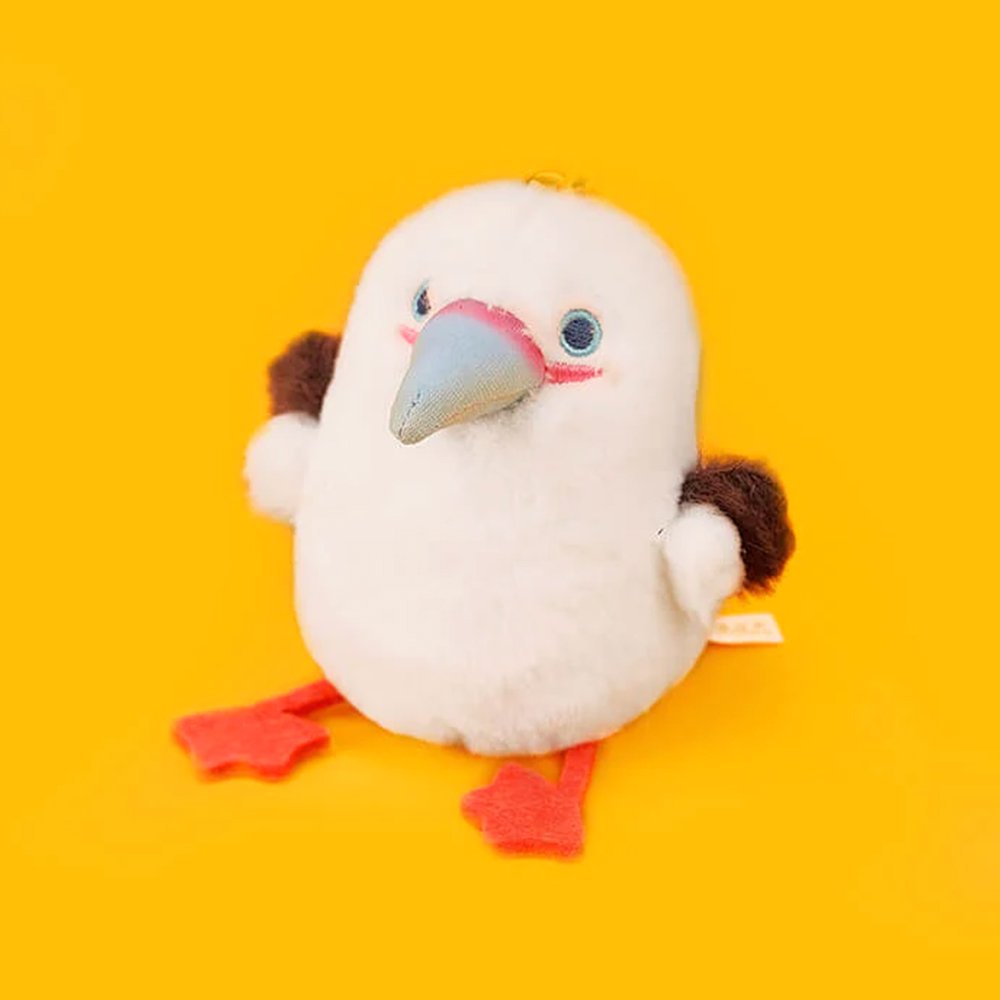 A round, fluffy white Red-footed Booby bird plush keychain featuring grey wings, a blue beak, and bright pink webbed feet
