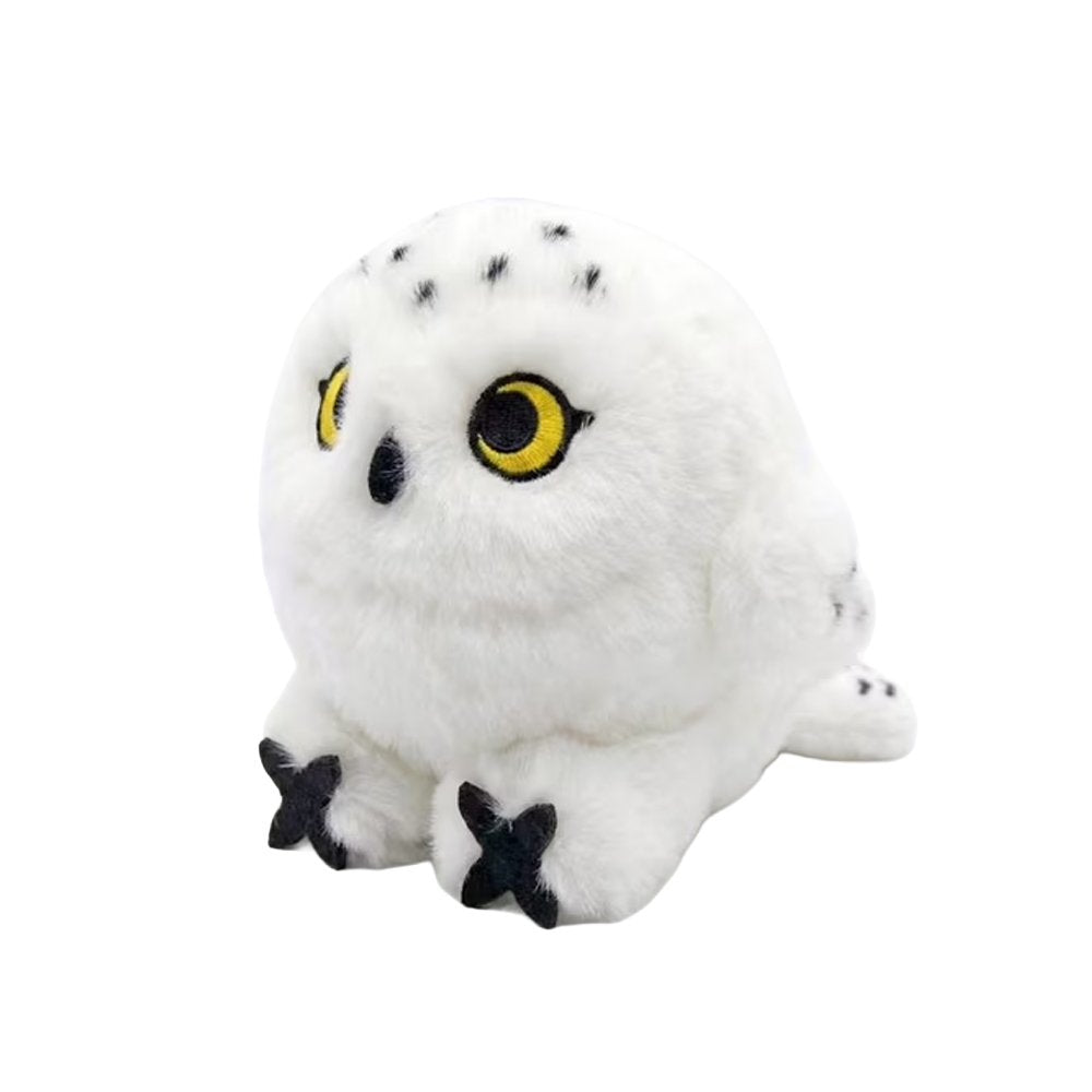 An adorable, round snowy owl plush keychain with fluffy white fur and black speckles on its head and tail. The plush features large, bright yellow embroidered eyes, a tiny black beak, and prominent black talons peeking out from its spherical body.