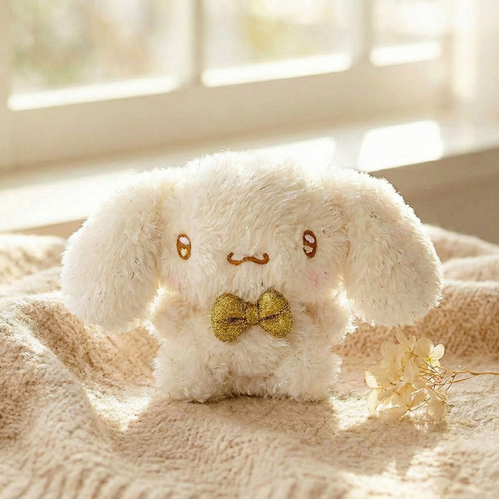 An officially licensed Sanrio Cinnamoroll plush keychain with sparkling cream-colored fur and a small metallic gold bow tie.