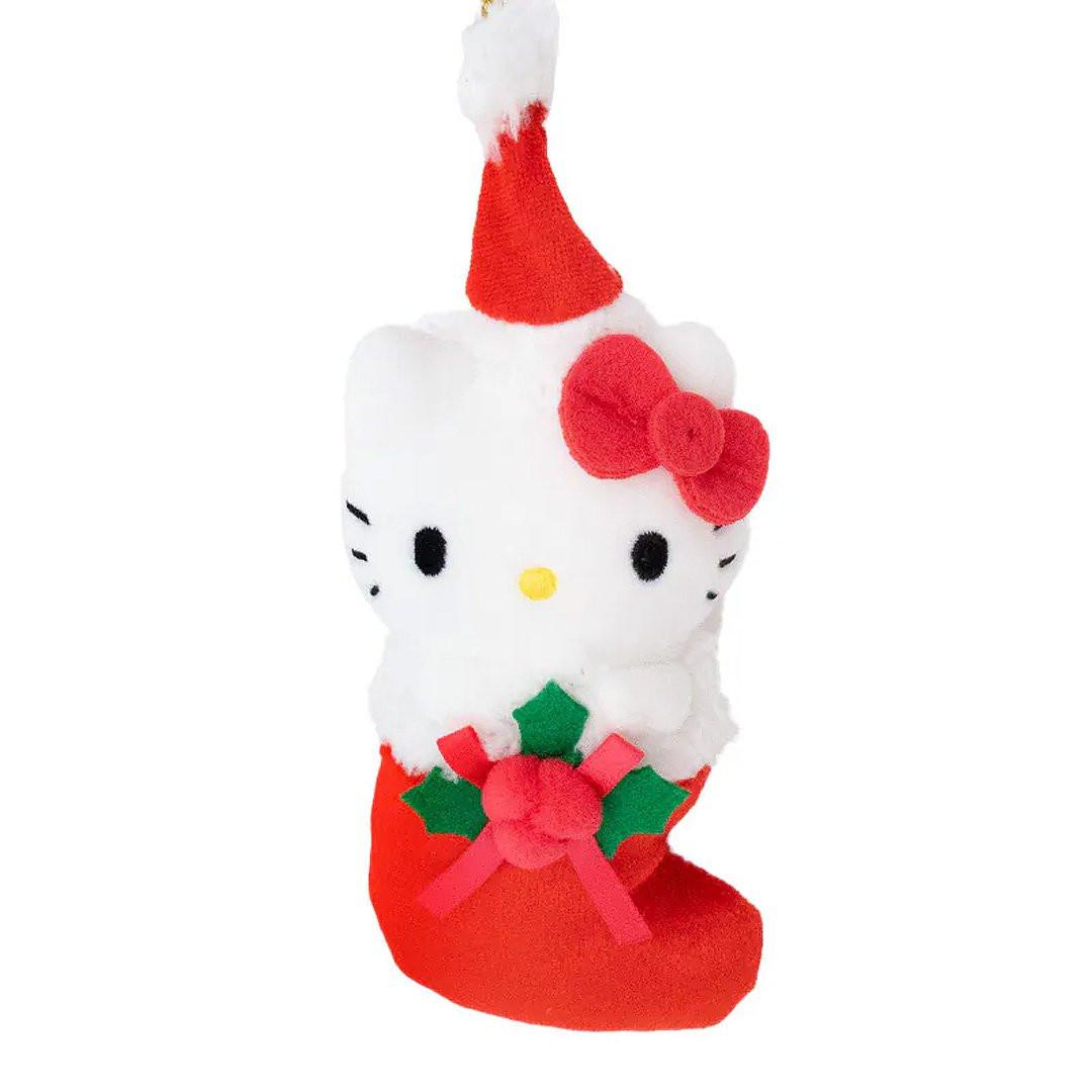 Sanrio Hello Kitty is dressed for the season wearing a red Santa hat with a white pom-pom while sporting his signature red bow. She sits snugly in a red Christmas stocking adorned with green holly leaves and a decorative ribbon. Crafted from soft plush material, this ornament has a cozy, huggable feel. The attached gold cord loop makes it easy to hang on your Christmas tree.