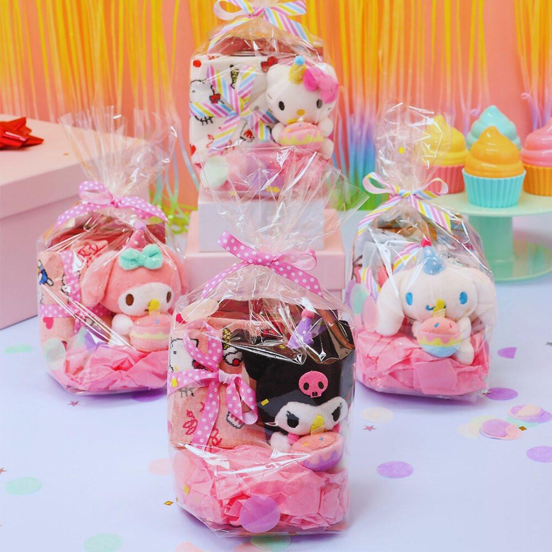 A collection of Sanrio Happy Birthday themed gift sets, each containing various colorful items such as plush keychains and socks, all packaged in clear gift bags with pink ribbons.
