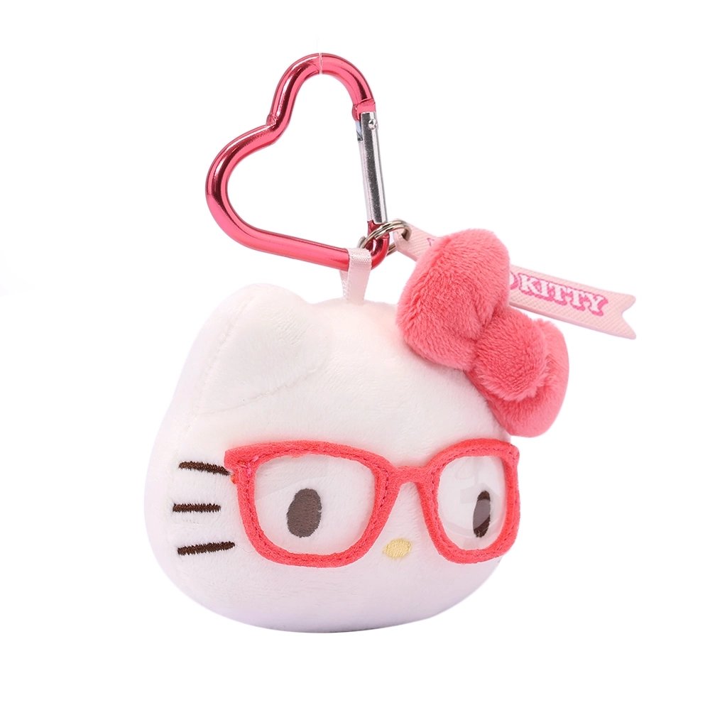 An officially licensed Sanrio Hello Kitty plush head keychain, wearing embroidered pink glasses and a textured pink bow. The keychain features a pink, heart-shaped metal carabiner clip and a woven fabric tag that reads "HELLO KITTY." The sturdy, heart-shaped carabiner in a matching metallic pink finish, makes it easy to clip onto backpacks, purses, or belt loops.