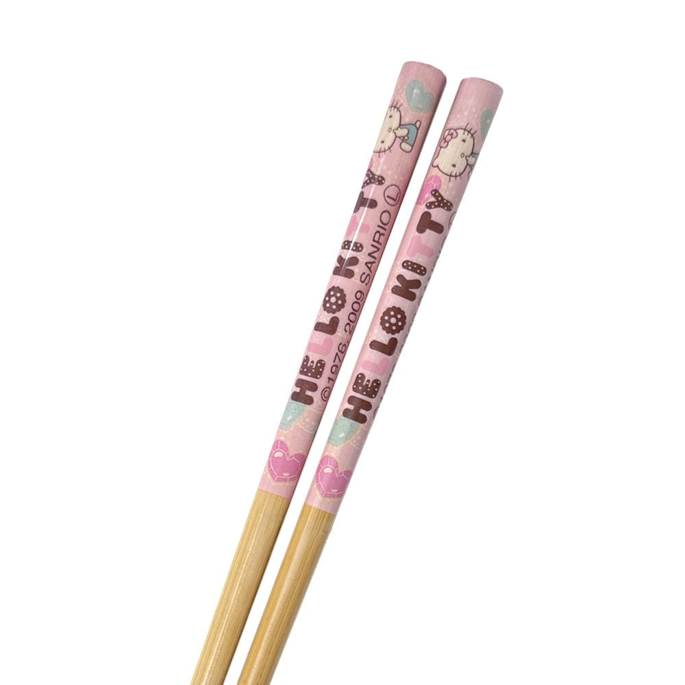 A pair of officially licensed Sanrio Hello Kitty bamboo chopsticks sealed in clear plastic packaging, featuring a pink upper handle decorated with Hello Kitty characters and text, and grooved tips at the bottom.