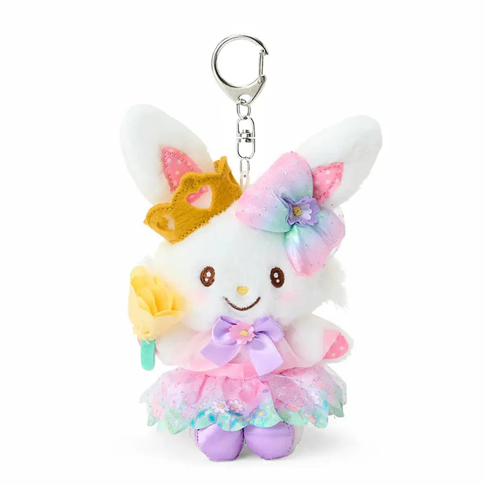 A plush keychain of the Sanrio character Wish me mell, a white bunny with pink-and-white polka dot patterns inside her ears. She is wearing a golden crown, a large rainbow-gradient bow, and a lavender-and-pink princess dress with a floral organza skirt. She holds a yellow flower and is attached to a silver metal lobster clasp.