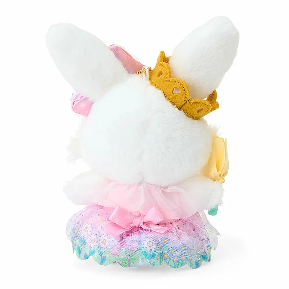 A plush keychain of the Sanrio character Wish me mell, a white bunny with pink-and-white polka dot patterns inside her ears. She is wearing a golden crown, a large rainbow-gradient bow, and a lavender-and-pink princess dress with a floral organza skirt. She holds a yellow flower and is attached to a silver metal lobster clasp.