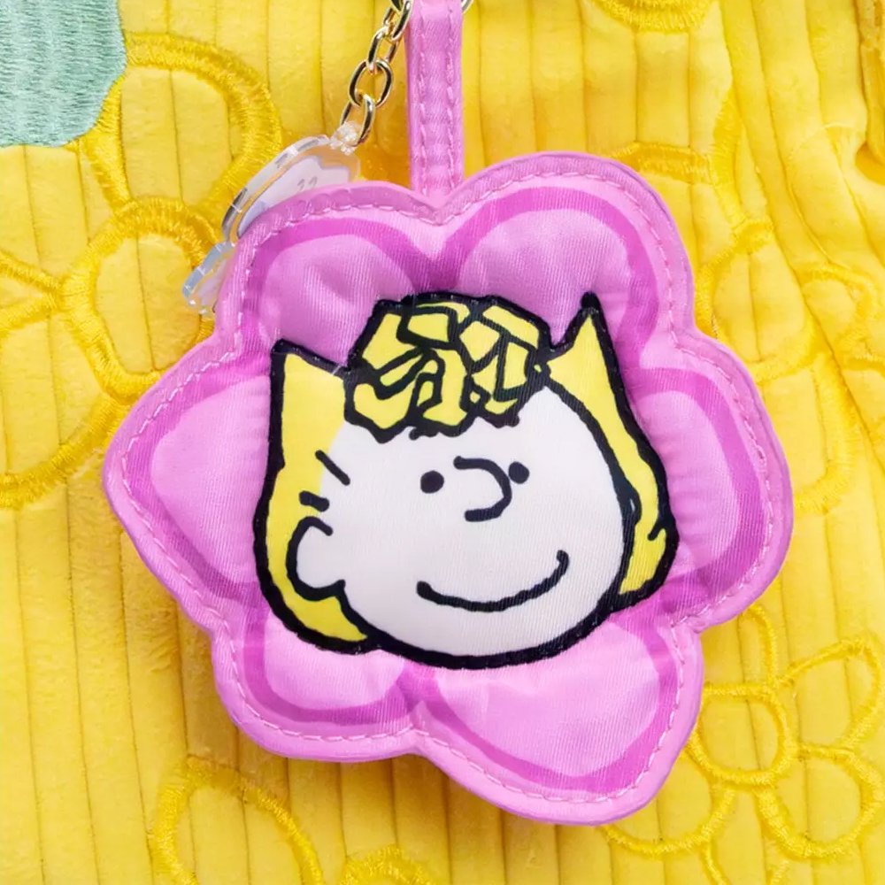 A collection of six colorful, flower-shaped Peanuts character pouch charms showcasing Snoopy, Woodstock, Charlie Brown, Lucy, Sally, and Linus