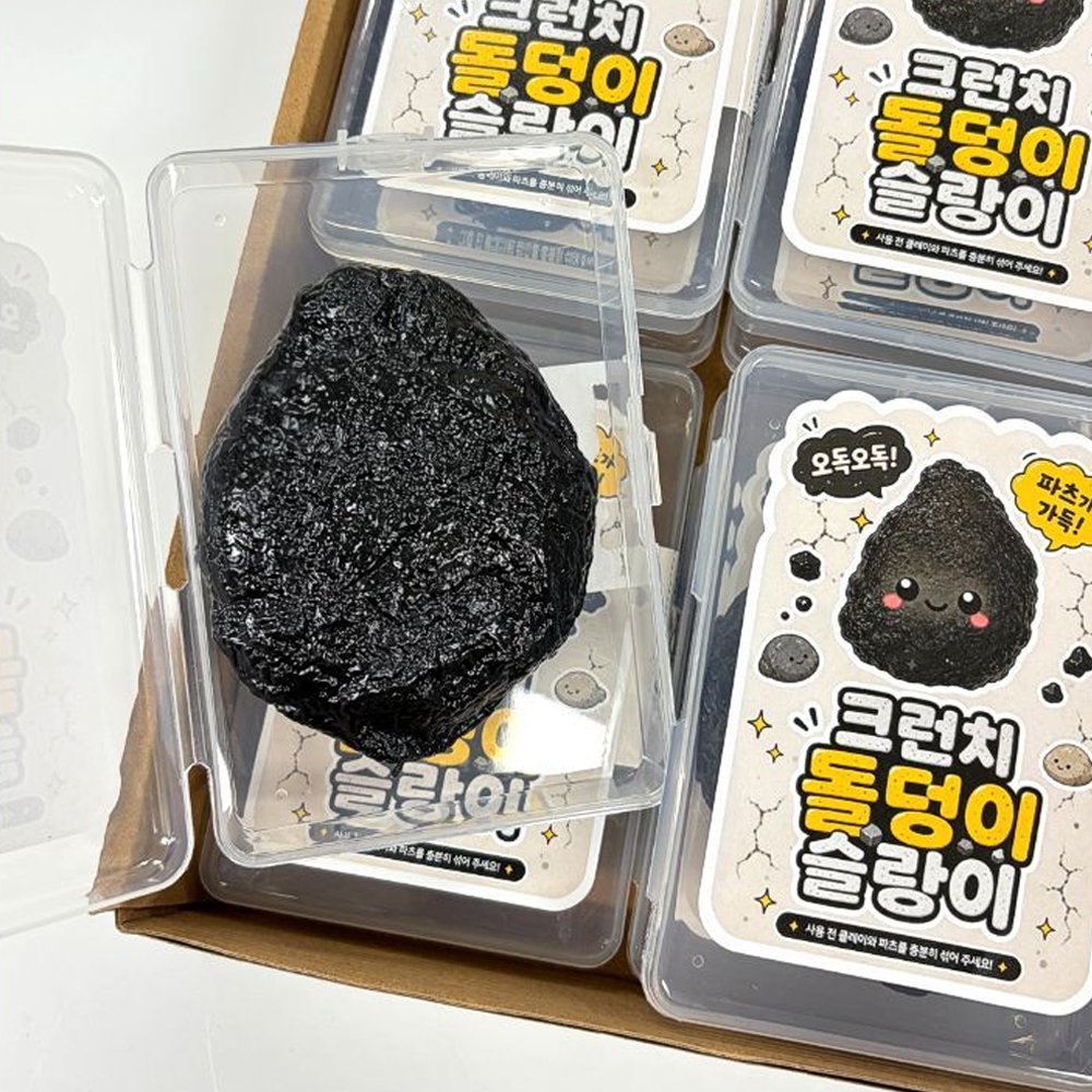 Open Charcoal Stone Crunch Squishy Slime inside a clear storage box placed in a multi-pack retail box, showcasing the unique volcanic rock design for fidget toy collectors and Christmas gifts
