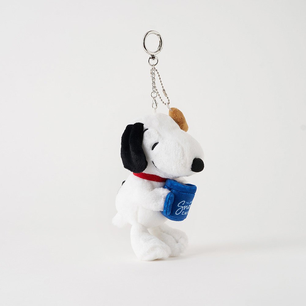 Snoopy Plush keychain is holding a blue mug with text on a white background