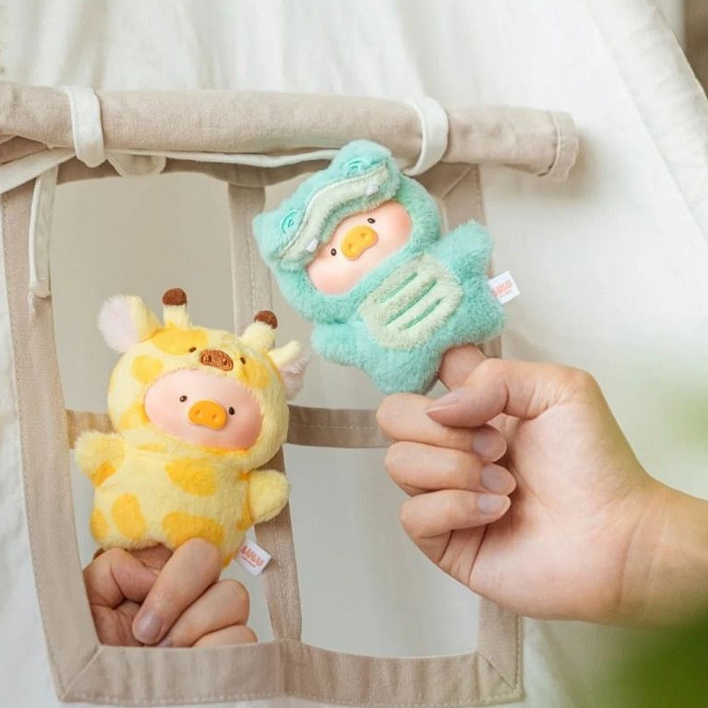 Two plush toys, one yellow giraffe and one blue creature, held by a hand against a neutral background.