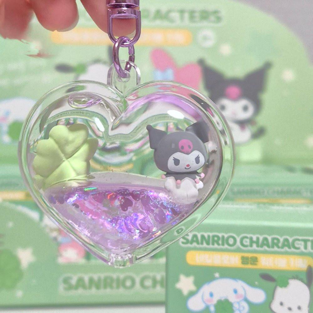 Heart-shaped keychain with a Kuromi inside, displayed against a blurred Sanrio product background.