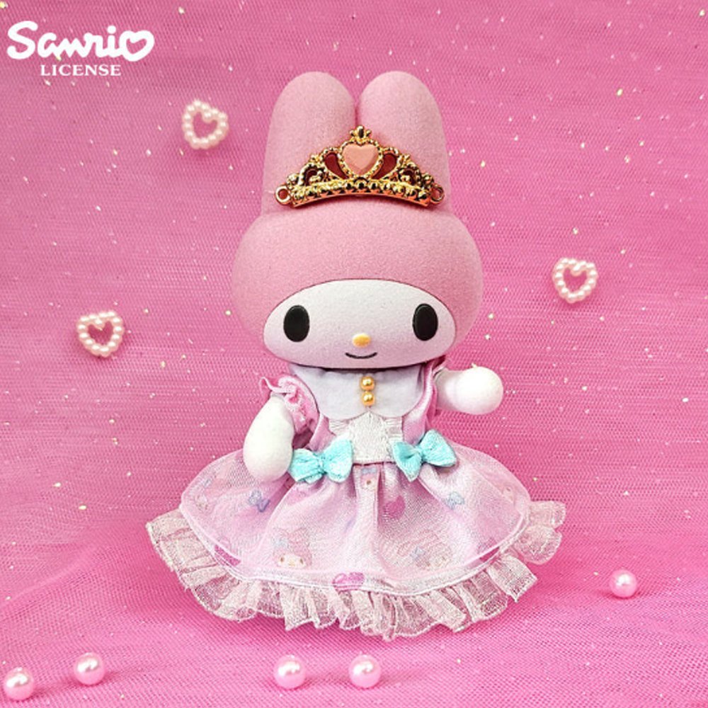 Sanrio My Melody Flocky Doll, a plush toy with intricate lace details, a removable outfit, and a sparkling tiara. The doll is pink with white and blue accents and is posed in a sitting position