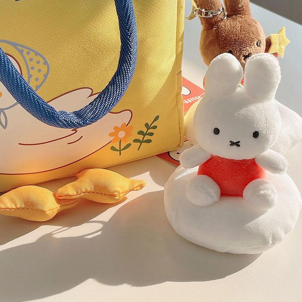 Plush keychain of Miffy character in an orange outfit sitting on the cloud