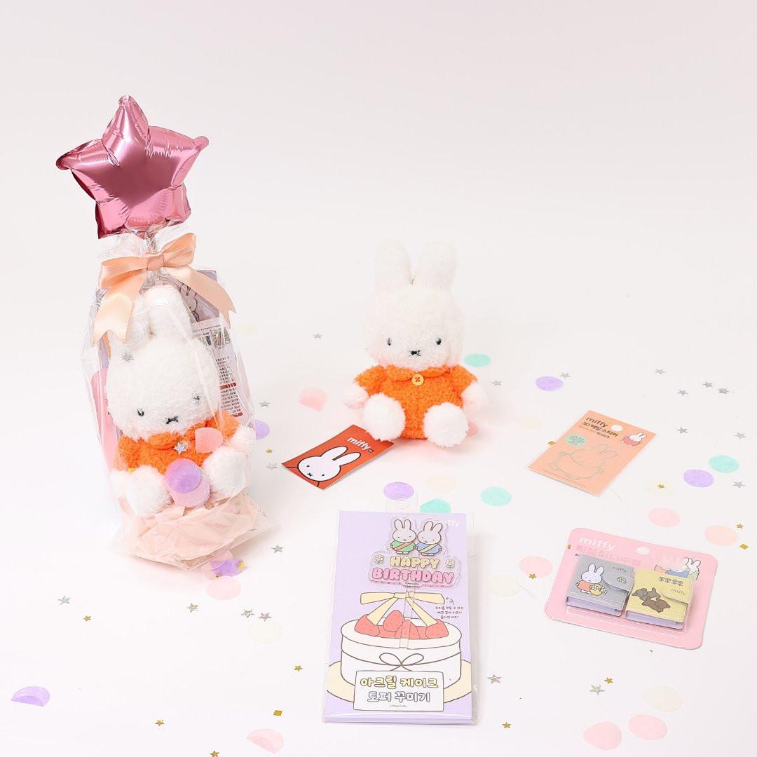 A collection of Miffy-themed birthday gifts including plush keychains, mini notebooks, metal deco stickers, a cake topper, and a letter set, all packaged with a 'Happy Birthday' theme.