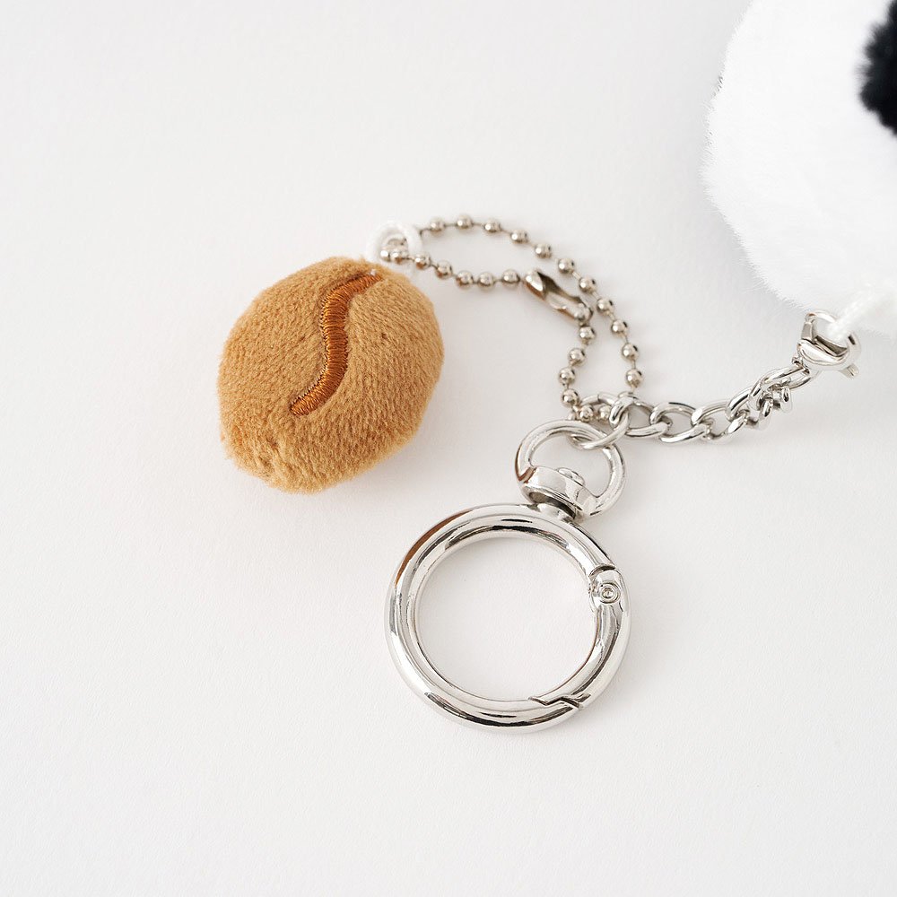 Silver keychain with a round, Snoopy pluhs with Coffee bean plush toy on a white background