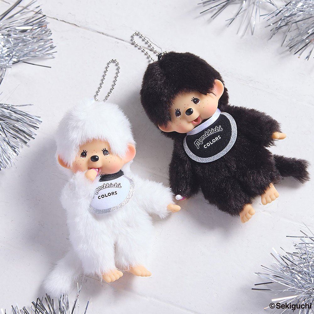 Two plush toys, one black and one white, with 'Monchhichi' branding on a white background.