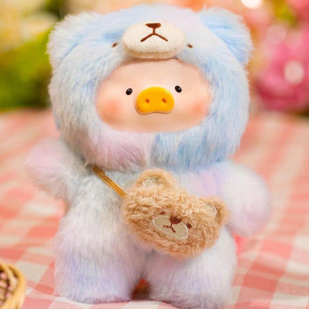 Plush toy bear in a colorful outfit with a heart, on a checkered fabric background.