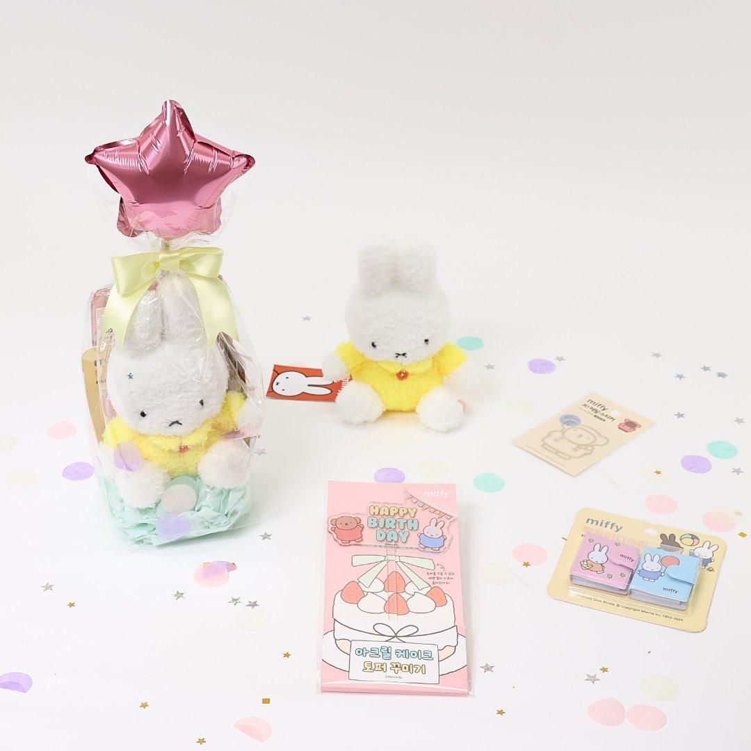 A collection of Miffy-themed birthday gifts including plush keychains, mini notebooks, metal deco stickers, a cake topper, and a letter set, all packaged with a 'Happy Birthday' theme.