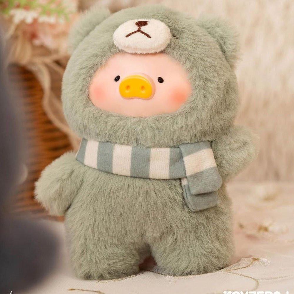 Plush toy bear in a green outfit with a striped scarf on a soft background